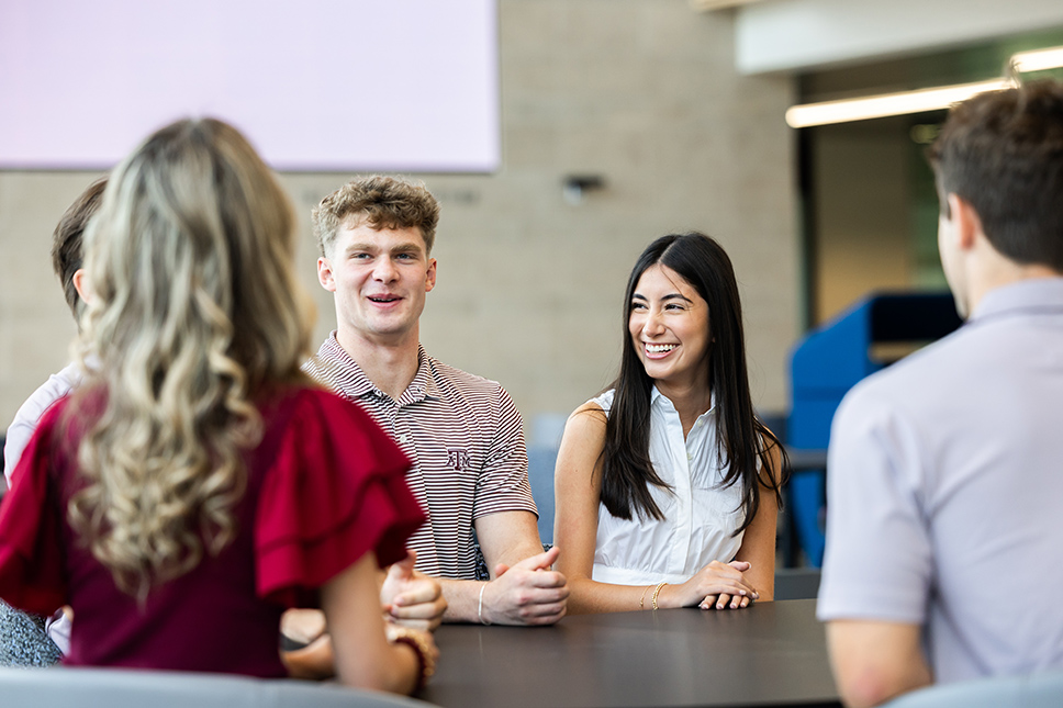 group of college students sitting at table and talking and laughing