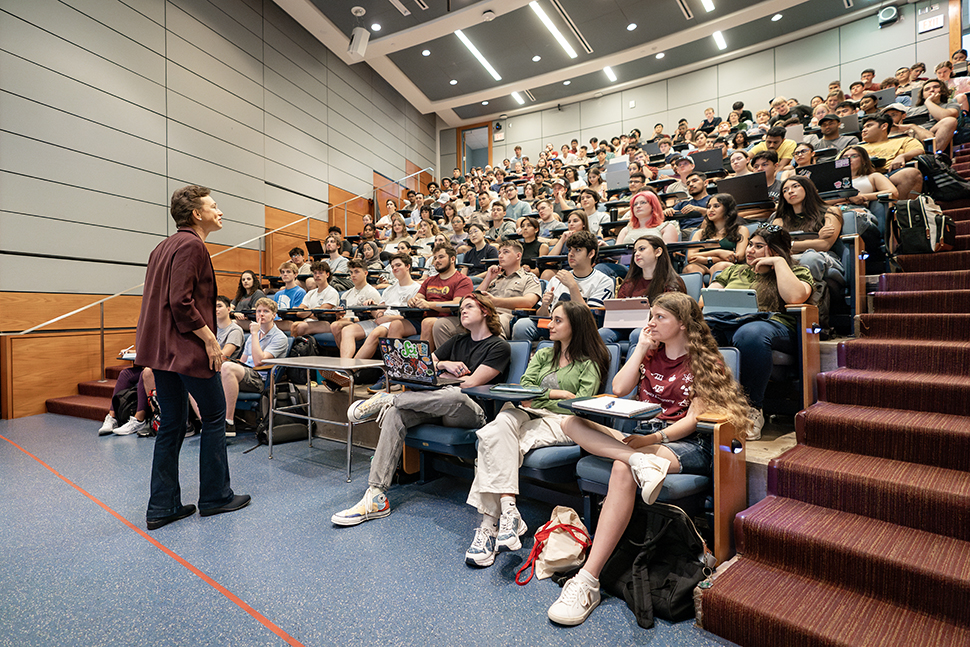 professor standing in front of full college classroom of students