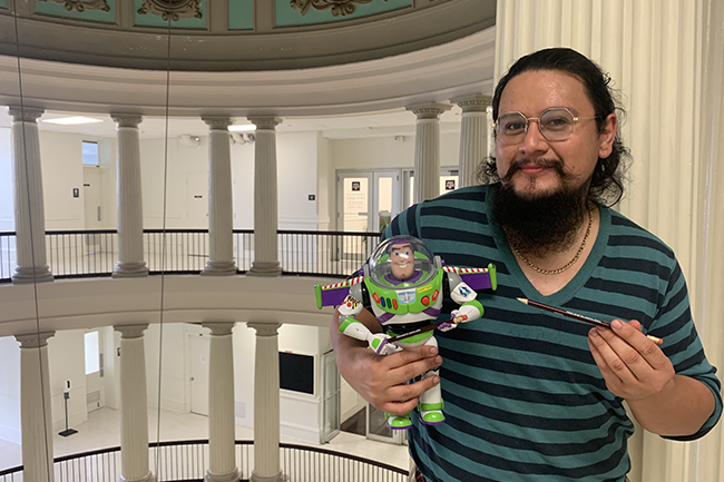 Communications Specialist II Reyes Ramirez holding Buzz Lightyear action figure