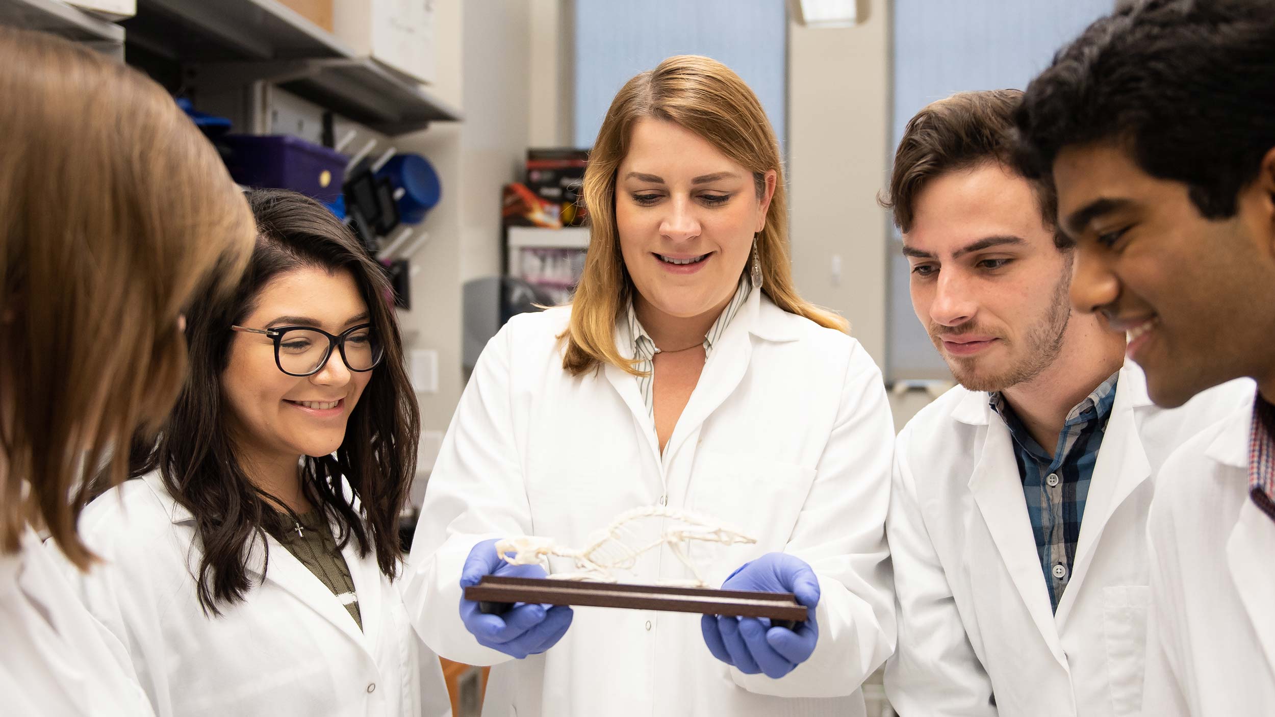 Faculty and students in a biology lab, smiling.