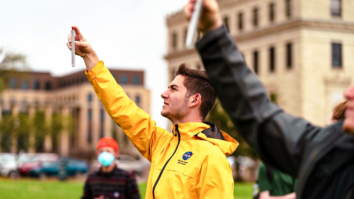 Two students holding research equipment in the air to collect atmospheric data