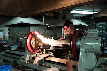 technician making glass blown object in workshop