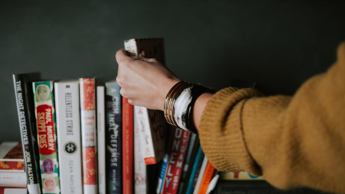 Person choosing a book from a rack of books