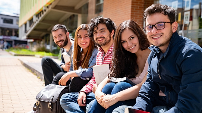 Row of smiling students sitting outdoors together