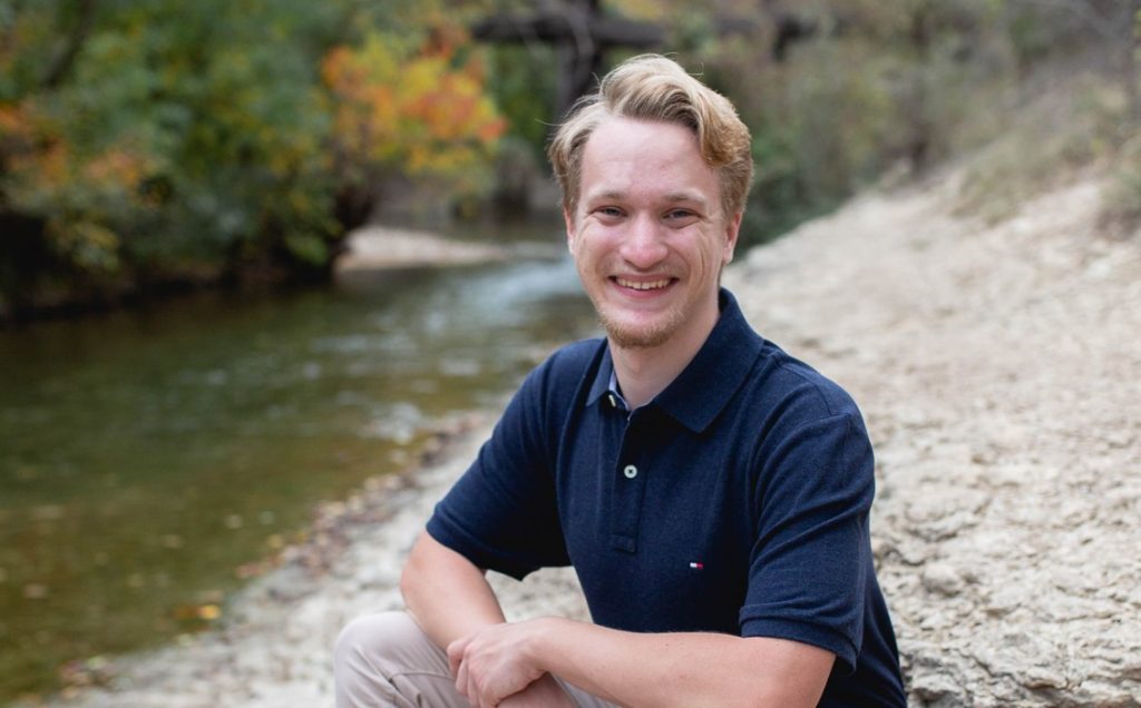 Caucasion man with blonde hair posing in front of river