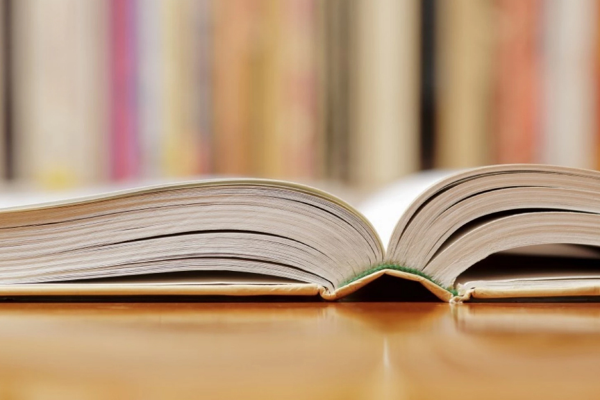 An open book lying on a table with a multicolored wallpaper background