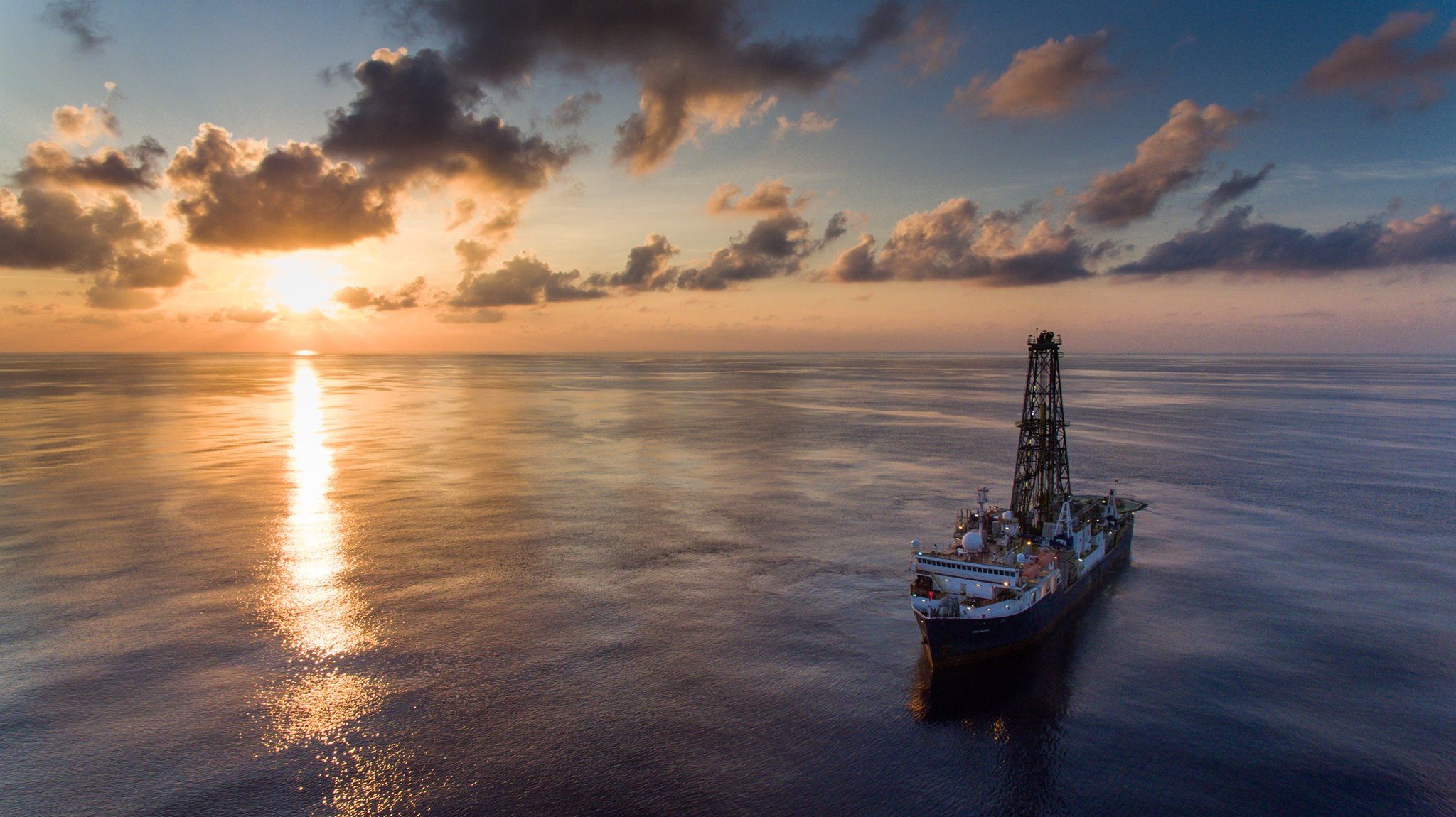 The JOIDES Resolution on the open ocean as the sun sets in the background