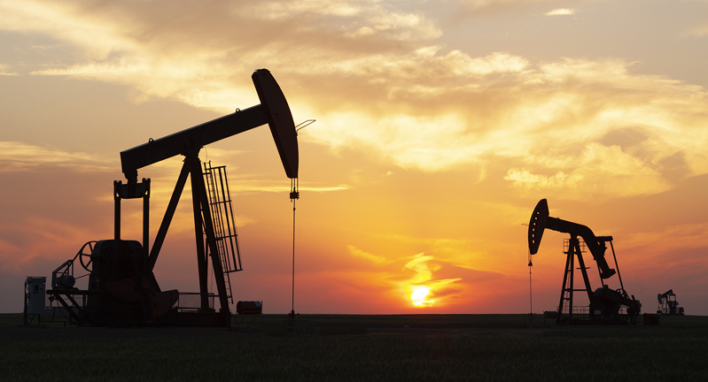 Pump jacks working in the field against a sunset backdrop