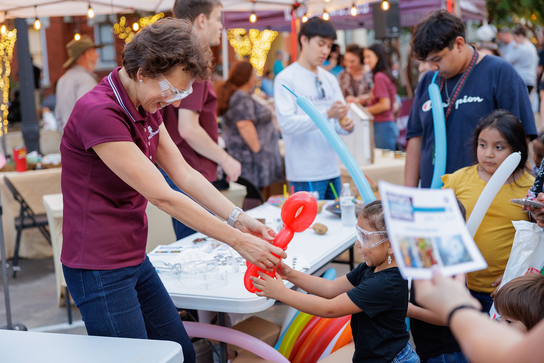 Texas A&M physicist Tatiana Erukhimova makes a balloon animal for a young participant at First Friday at Downtown Bryan