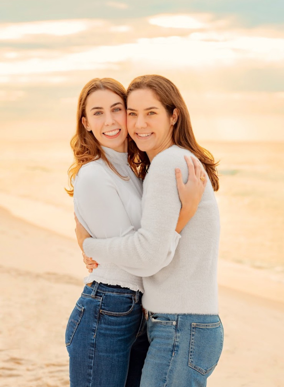 Sisters SarahBeth (left) and Hannah Joy Boothe hug while standing on a beach