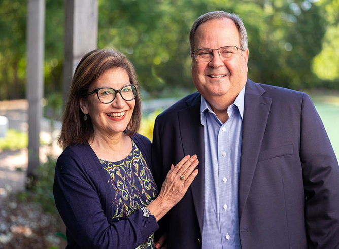 Rita and Dr. Kevin Gamache smile for the camera while posing in an outdoor setting