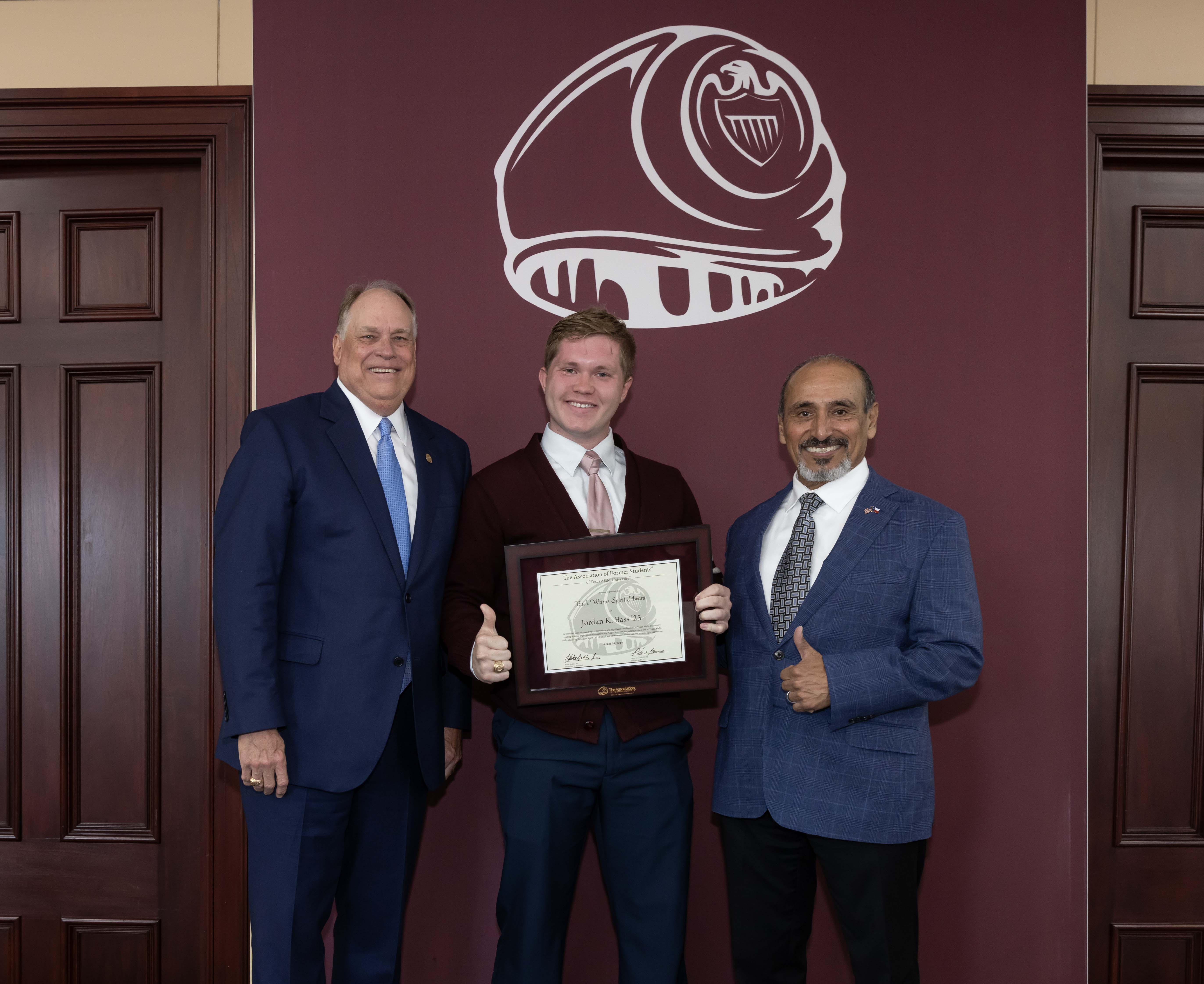 2024 Texas A&amp;M University physics graduate Jordan Bass (center), posing with Porter S. Garner III '79, executive director of The Association of Former Students (left) and Brig. Gen. (Ret) Joe E. Ramirez Jr. '79, Texas A&amp;M Vice President for Student Affairs, after receiving the 2024 Buck Weirus Spirit Award