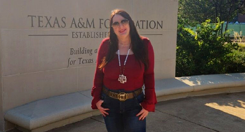 1990 Texas A&M University English graduate Susan Smallman, standing in front of the Texas A&M Foundation sign on the Texas A&M campus