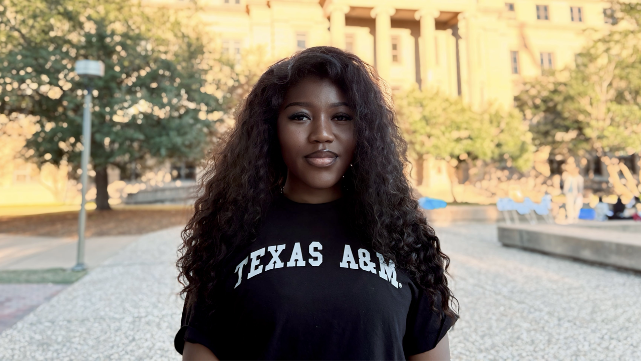 Jewel Fanyui wearing a Texas A&M T-shirt, standing in front of the Academic Building on the campus of Texas A&M University.