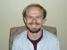 Man smiling at camera in white shirt.