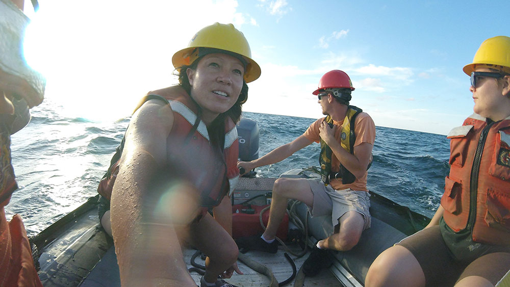 Four student researchers on a small boat on a large body of water