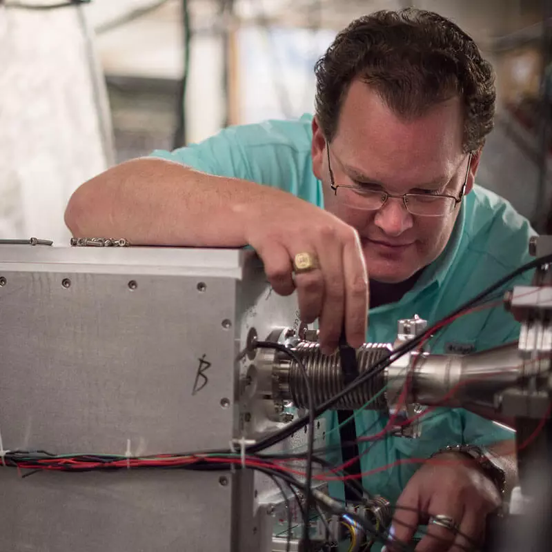 man in front of cyclotron machine