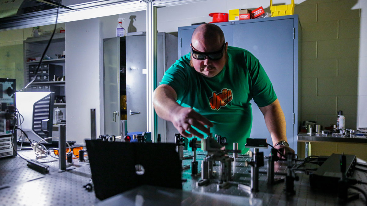 Graduate student working with spectroscopy equipment in a lab.