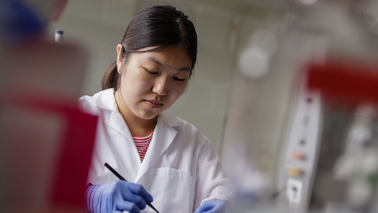 Researcher wearing a lab coat and sterile gloves